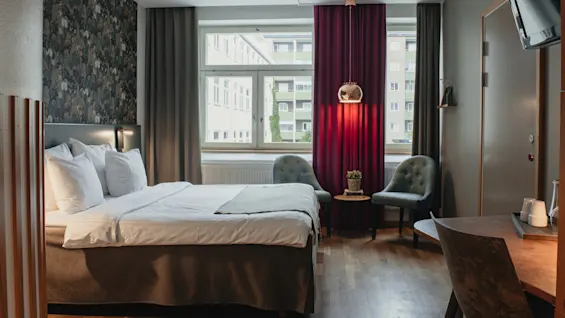 A cozy hotel room at Home Hotel Uppsala with a comfortable bed, seating area, and a view of the city outside.