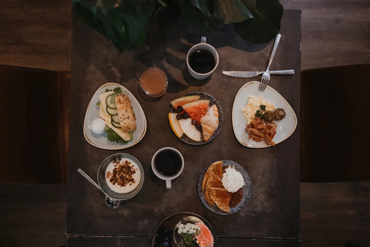 A delightful breakfast spread at Home Hotel Uppsala, featuring a variety of dishes including eggs, bacon, fruits, pastries, and coffee.
