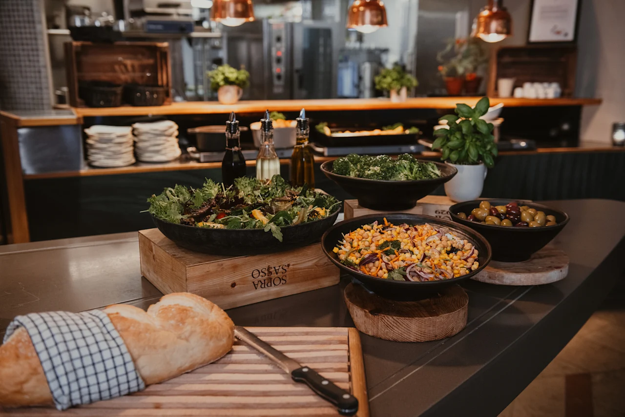 A vibrant buffet spread at Home Hotel Uppsala featuring fresh salads, olives, and a rustic loaf of bread, ready for serving.