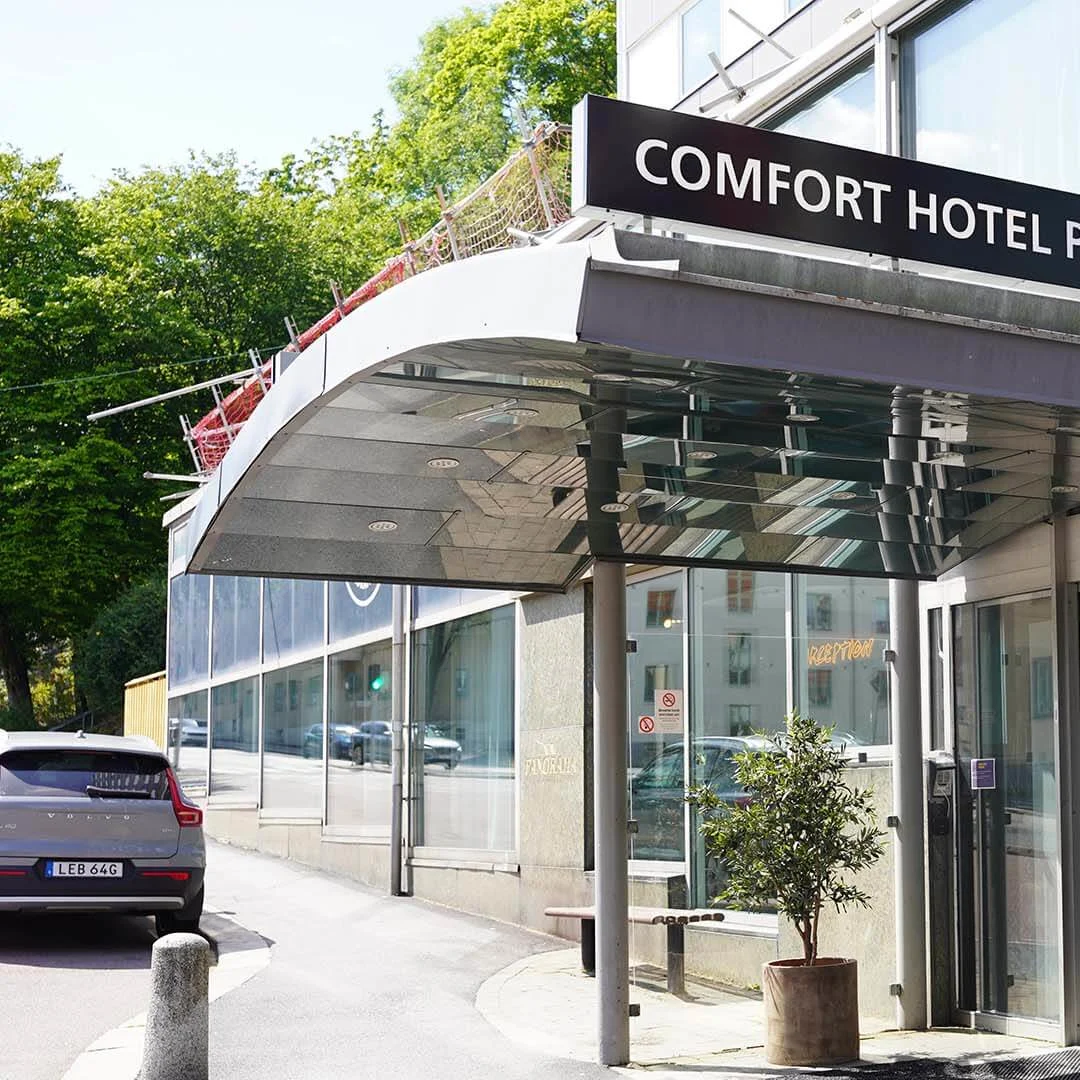 The Comfort Hotel Panorama entrance with a sign, on a sunny day with a clear sky.