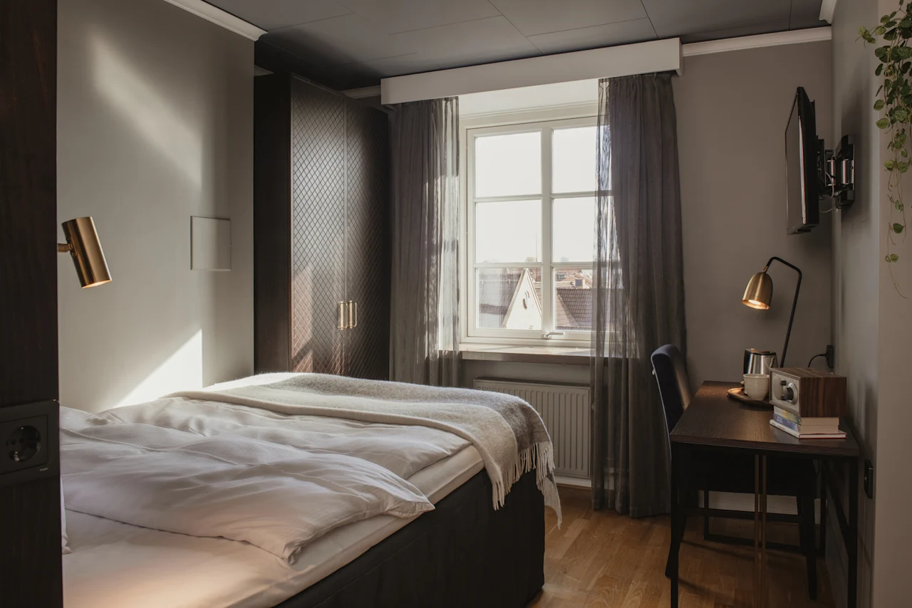 Ett mysigt hotellrum på Home Hotel Grand, Helsingborg, med en bekväm säng, en skrivbordshörna och naturligt ljus från fönstret.