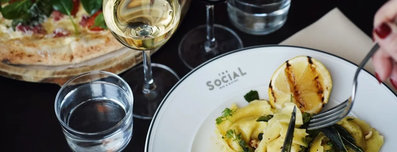 Two people eating pasta and meat at The Social Bar & Bistro.