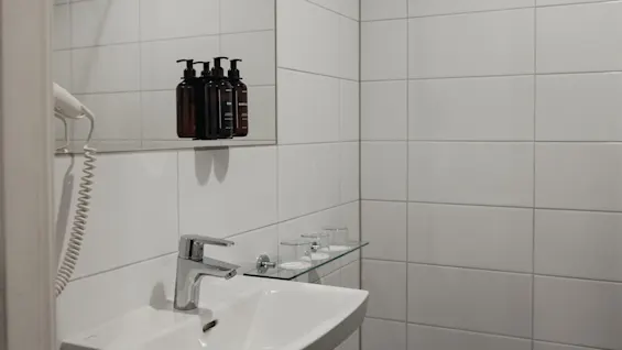 Det välutrustade badrumshandfatet på Home Hotel Bristol, med en spegel som reflekterar toalettartiklar och fräscha glas.