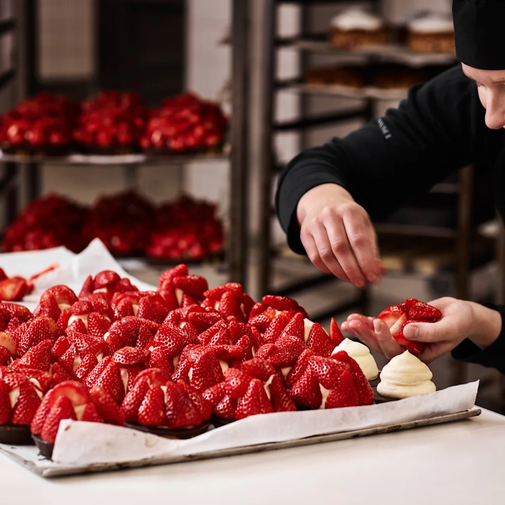 Female baker decorating exquisite strawberry cakes at Lagkagehuset in Copenhagen