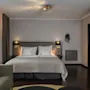 A cozy hotel room featuring a large bed, a comfortable sofa, and a separate bunk bed area for additional guests.