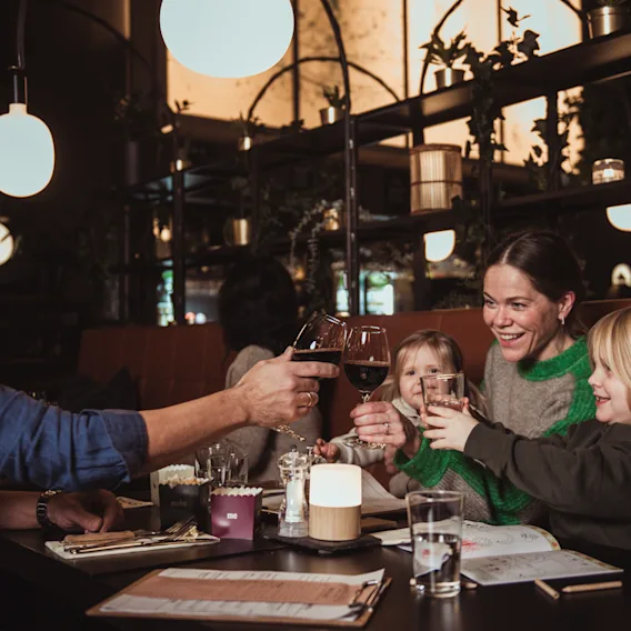 En familj som skålar tillsammans under en trevlig middag på en mysig restaurang.