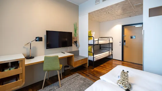 A welcoming hotel room with a dedicated workspace, entertainment area, and multiple sleeping options including bunk beds.