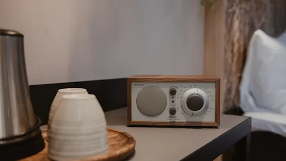 Tyylikäs puinen radio Bluetoothilla ja MODEL ONE BT:llä yöpöydällä vedenkeittimen ja kuppien vieressä luoden viihtyisän tunnelman.