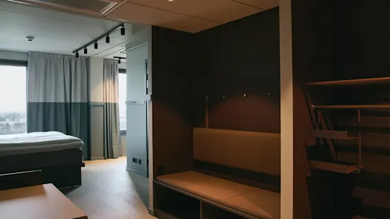 Ett modernt och funktionellt hotellrum på Stopover Hotel Falkenberg, med en bekväm säng, sittgrupp och praktiska förvaringslösningar.