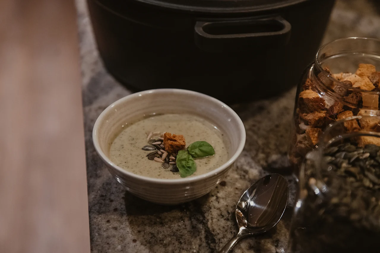 A delicious bowl of soup with croutons, seeds, and basil, ready to be enjoyed at Home Hotel Kung Oscar.