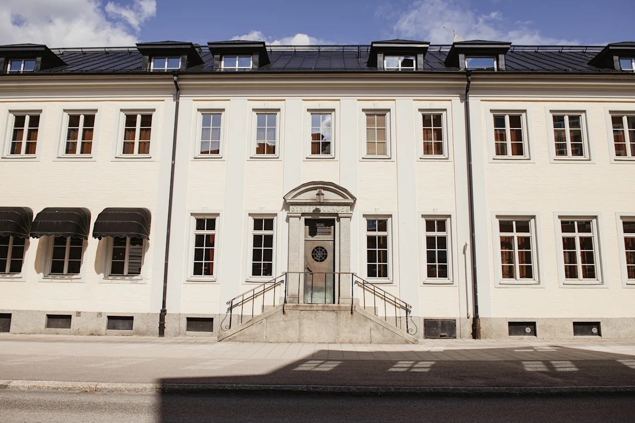 En kremfarget bygning med mørkt tak, mange vinduer og en sentral inngang med trapper. Teksten over døren lyder SYSTEMBOLAGET.