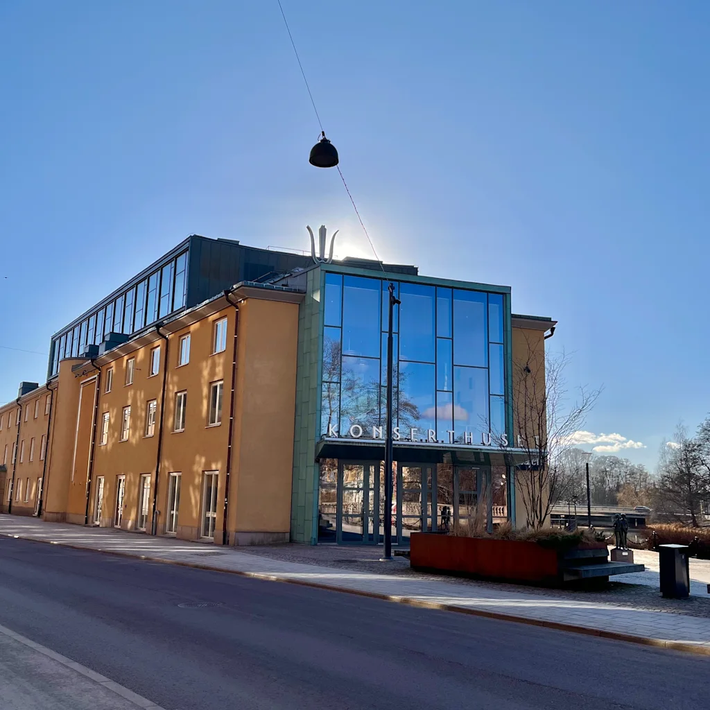 Örebro Konserthus, Svenska kammarorkestern. A sunny exterior view of a building with 'KONSERTHUS' on its glass facade.