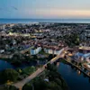 Luftfoto av en kystby i skumringen, med en elv som snor seg gjennom opplyste bygninger og en bro.