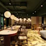A modern hotel lobby and lounge area with a long communal table stylish seating and warm spherical pendant lights