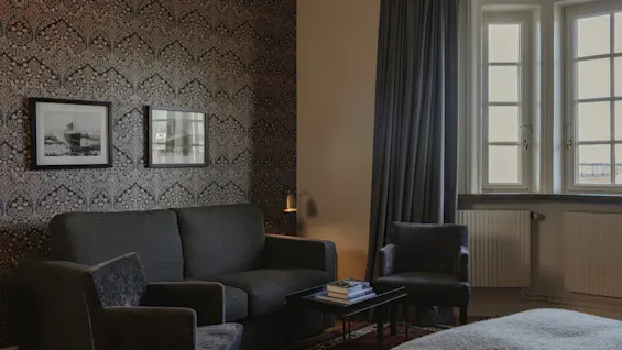 Ett varmt och inbjudande hotellrum på Home Hotel Grand, Helsingborg, med en bekväm sittgrupp och elegant inredning.