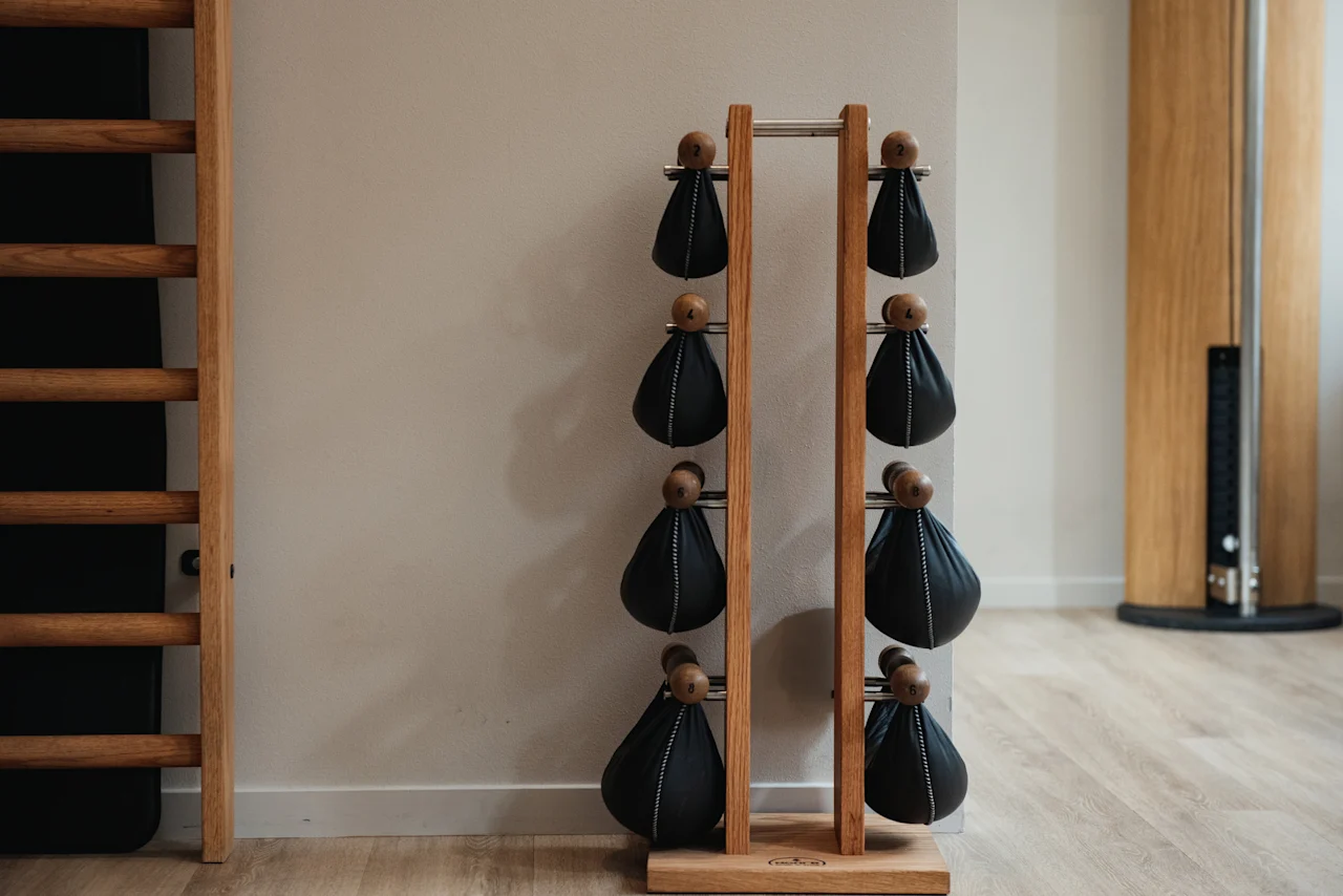 A modern fitness area at Home Hotel Uppsala with a wooden rack holding black weights and a wooden wall ladder.