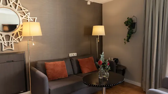 An inviting living room with a comfortable sofa, a coffee table adorned with flowers, and warm lighting from floor lamps.