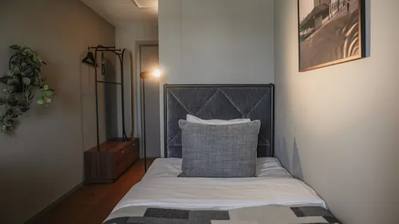 Ett välkomnande hotellrum med en enkelsäng, mjuk belysning och minimalistisk design, perfekt för en avkopplande vistelse.