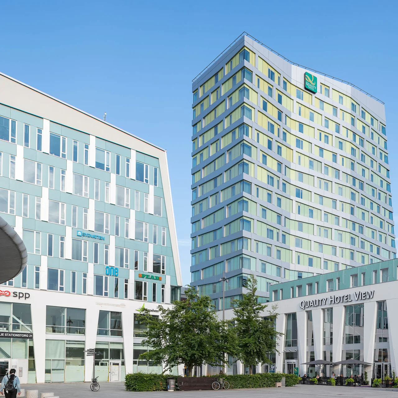 A tall, modern building with a patterned facade stands prominently; adjacent is the Quality Hotel View. Nearby are trees and signs reading "SYDVÄSTEN," "ONE," "SPP," and "PEAB."