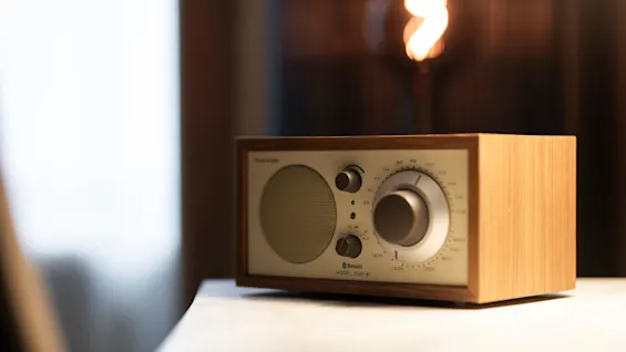 A classic wooden radio with a cream face, showing Bluetooth and MODEL ONE. Home Hotel Grand Bodø.