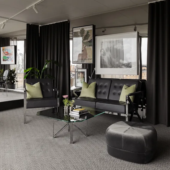 Stratum Suite på Clarion Hotel Sign i Stockholm. Modern lounge med svarta möbler, glasbord och konst. Text: STOCKHOLM, GALLERIA MYNT.
