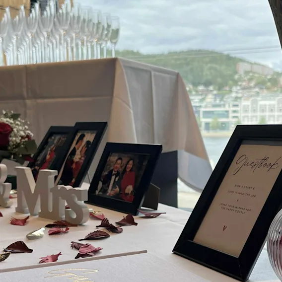 Et festlig borddekking for en spesiell anledning, pyntet med innrammede minner, blomsterarrangementer og "Mr & Mrs" dekor.