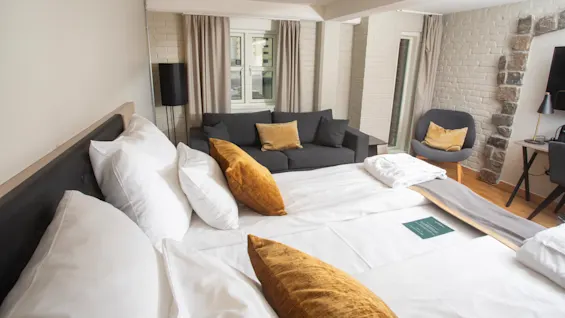 Deluxeroom at Home Hotel Bryggeparken, made bed with yellow pillows and sofa