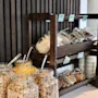 Jars of cereal and seeds are displayed on wooden shelves in a buffet setting, with labels: "Sojasa Krouker," "Fruesli Krouker," and "Pean øtter" beside small stacked plates.
