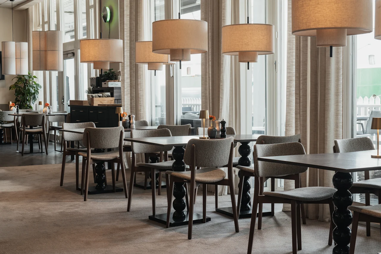 Et moderne og indbydende restaurantinteriør med komfortable siddepladser, elegant belysning og store vinduer, der giver naturligt lys.