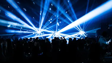 Eloisa yleisö nauttimassa tapahtumasta dynaamisten sinisten laservalojen ja discopallojen luodessa energisen tunnelman.