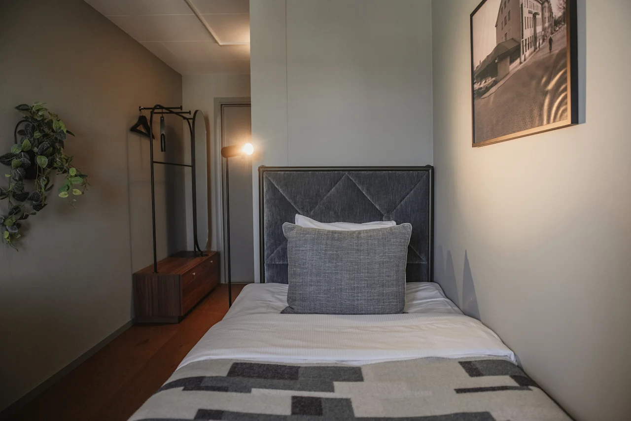 Ett välkomnande hotellrum med en enkelsäng, mjuk belysning och minimalistisk design, perfekt för en avkopplande vistelse.