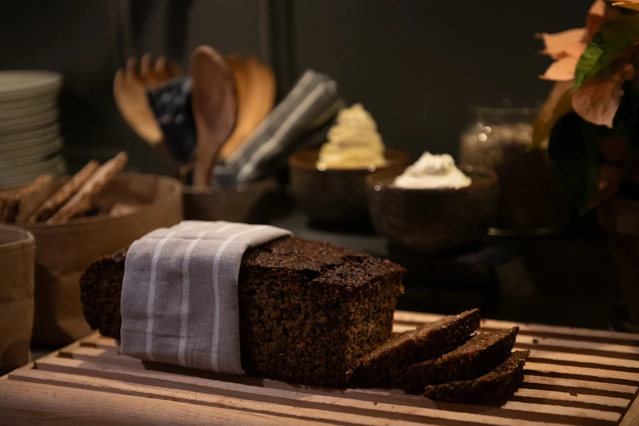 A delicious loaf of dark bread, partially sliced, on a wooden board at Home Hotel Kung Oscar, ready for a meal.