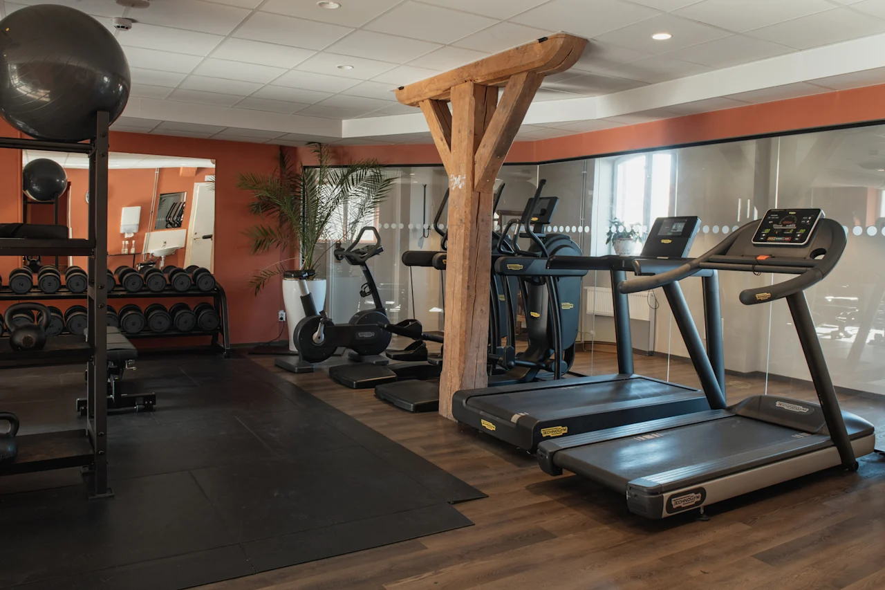 Et veludstyret fitnesscenter med løbebånd, motionscykler og frie vægte, klar til en træningssession.