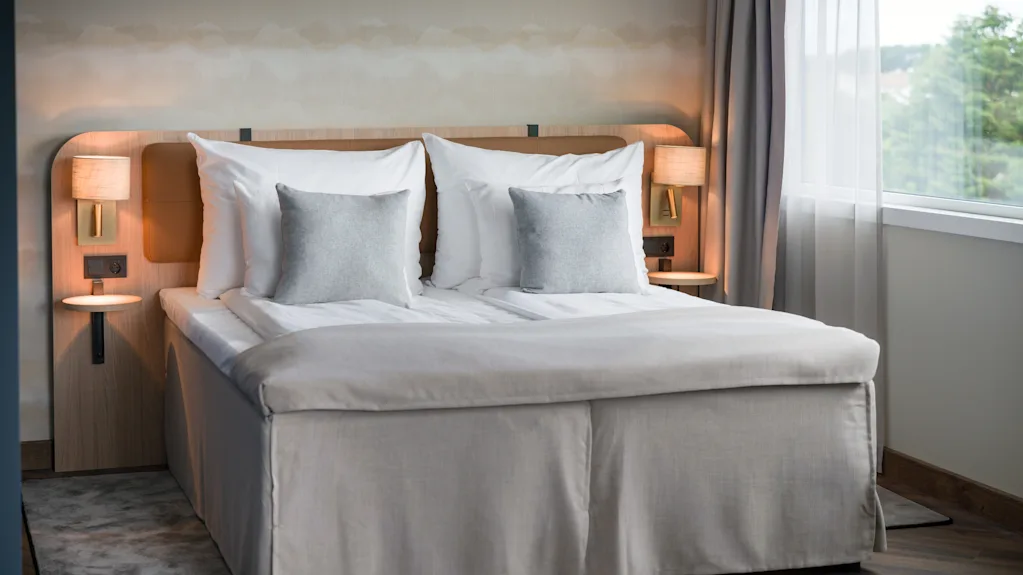 Pedattu parivuode valoisassa hotellihuoneessa ikkunan vieressä.