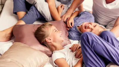 Barn skrattar i en hotellsäng