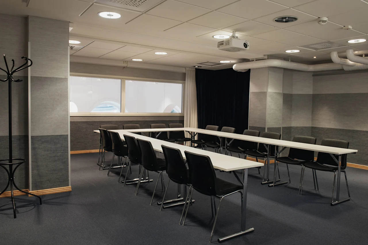 Ett konferensrum på Home Hotel Grand, Helsingborg, med bord och stolar arrangerade i en U-form, redo för ett möte.