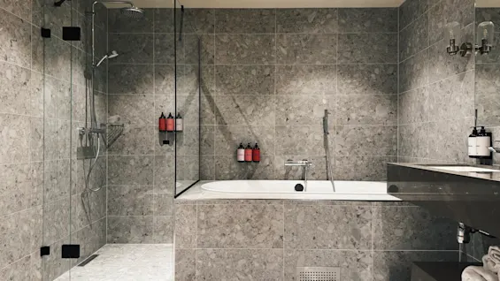 Ett modernt badrum med dusch och badkar, med elegant grått kakel och moderna armaturer.