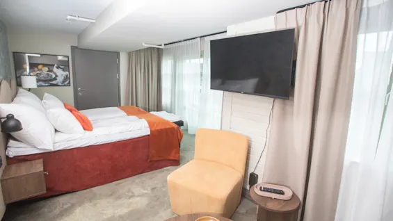 Moderni ja kutsuva hotellihuone Home Hotel Bryggeparkenissa, jossa on mukava sänky, seinälle asennettu televisio ja viihtyisä oleskelualue.