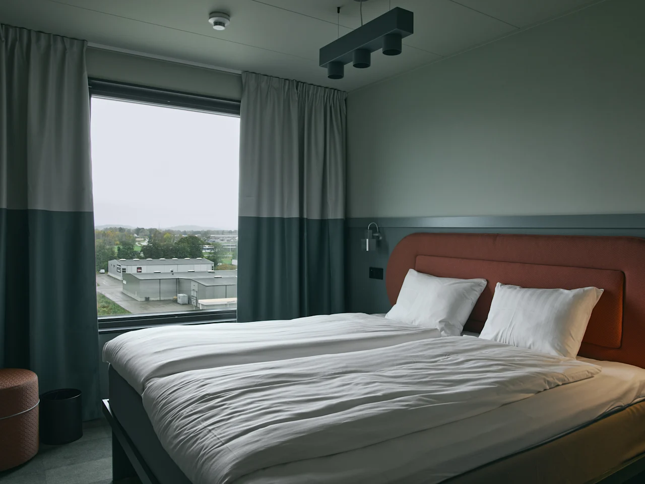 Ett bekvämt hotellrum på Stopover Hotel Falkenberg med två enkelsängar och fönsterutsikt över det omgivande landskapet.