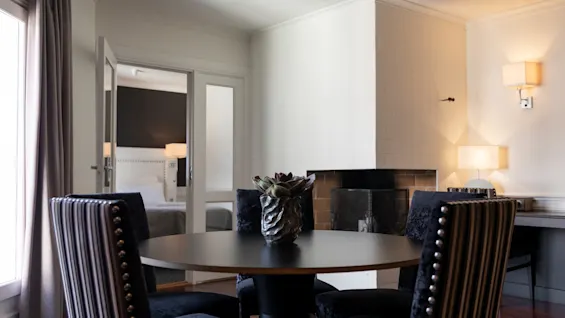 En hyggelig hotelsuite med spiseplads og et soveværelse synligt gennem en åben dør.