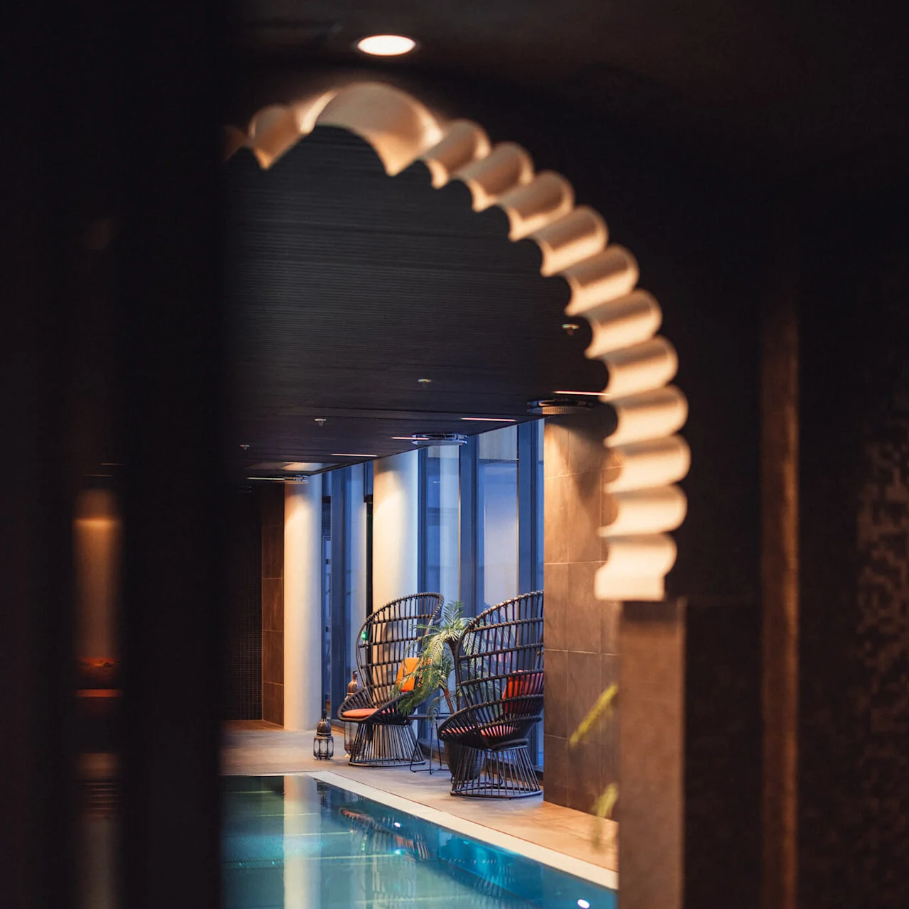 Två rottingstolar bredvid en inomhuspool, upplysta av varma ljus, i en fridfull miljö på spa på Lily Country Club i norska Klöfta.
