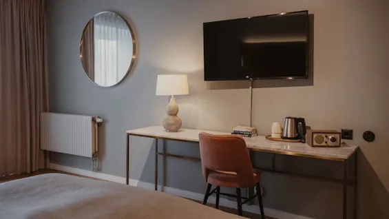 Et stilfuldt hotelværelse med et veloplyst skrivebordsområde, et stort tv til underholdning og en behagelig seng til afslapning.