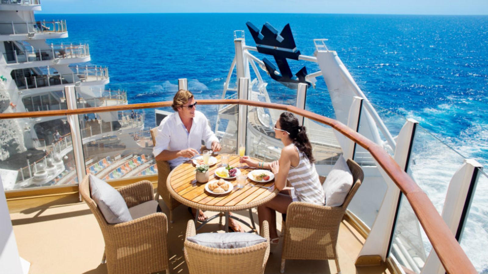 Kvinne og mann spiser frokost i solen på sin lugarbalkong på cruise
