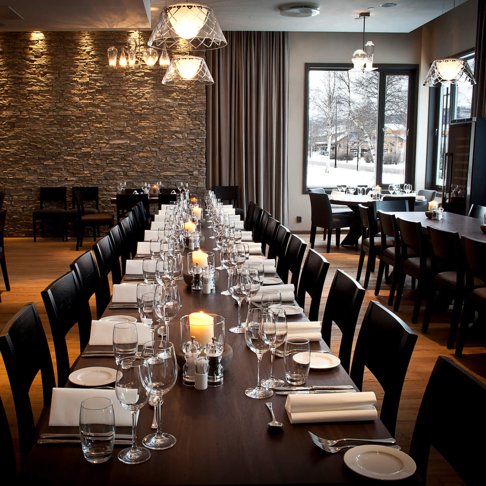 Restaurant with a set long table and snowy views outside at Quality Hotel™ Skifer in the norwegian ski town of Oppdal.