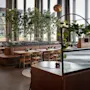 Valoisa ja moderni ravintolan sisätila, jossa on puupöytiä, nahkaistuimia ja koristeellisia sisäpuita.