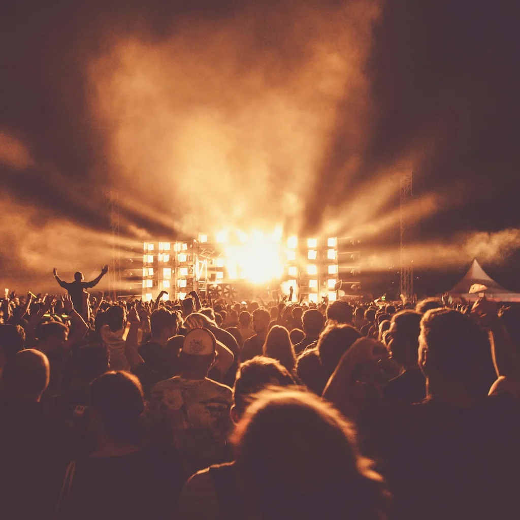 People with their hands in the air at a concert at night.