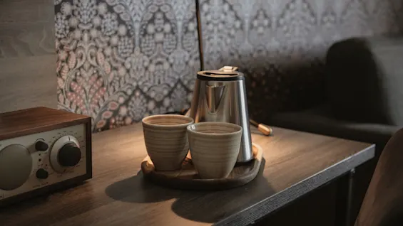 En mysig hörna på Home Hotel Grand, Helsingborg, med en vattenkokare, två koppar och en radio på ett träbord. MODEL ONE.