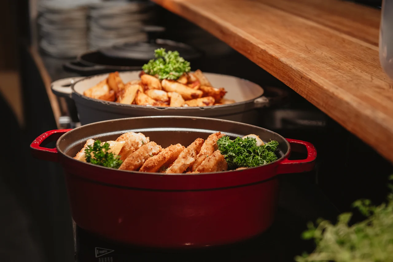 A warm buffet selection at Home Hotel Uppsala, featuring golden fried dishes and seasoned potato wedges, ready for guests.