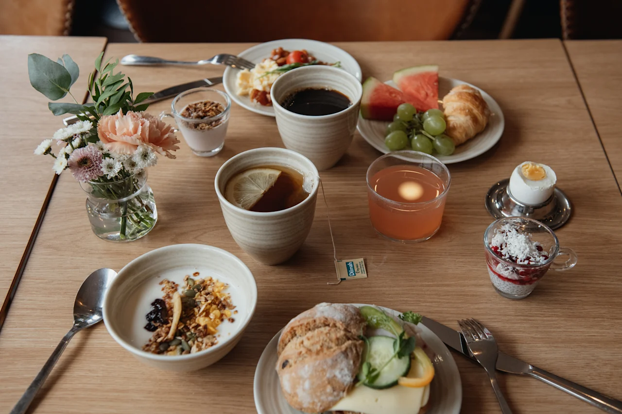 A table laden with a delightful breakfast spread including coffee, tea, juice, pastries, fruit, and savory dishes.