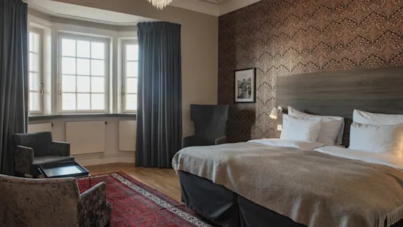 Ett elegant och bekvämt hotellrum på Home Hotel Grand, Helsingborg, med en stor säng och ett ljust burspråk.